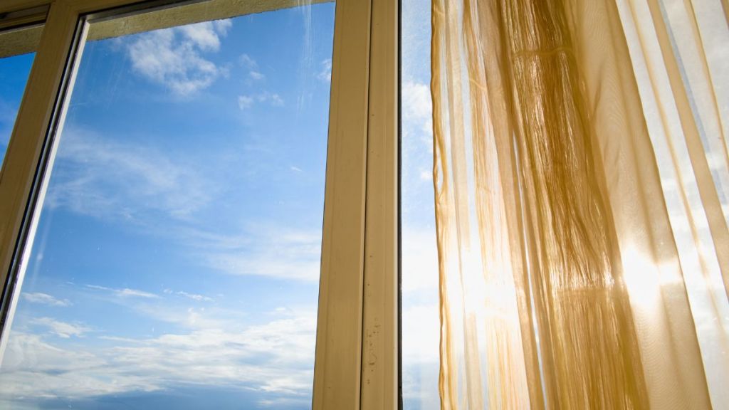 Soleil d’été traversant un rideau trop fin dans une maison en pleine canicule